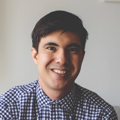 Brian Kooiman, Ad Hoc Group. A young man with short dark hair smiles at the camera, wearing a blue and white checkered shirt, against a plain light-colored background.