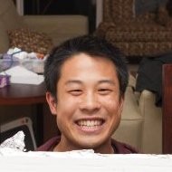 Jeffrey Wang, Google Nest. A man with short dark hair is smiling widely at the camera. The background shows a table with various items and a beige chair.