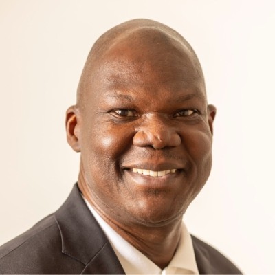 Joseph deGraft-Johnson, Salt River Project. A man with dark skin wearing a black blazer and white shirt smiles at the camera against a plain, light background.
