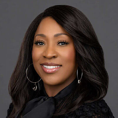 Angelita Gardner-Kitrell Dominion Energy. Woman with long dark hair, hoop earrings, and a black top, smiling against a plain gray background.