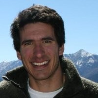 Noah Lieb, Apex Analytics. Man smiling outdoors with mountains and blue sky in the background.