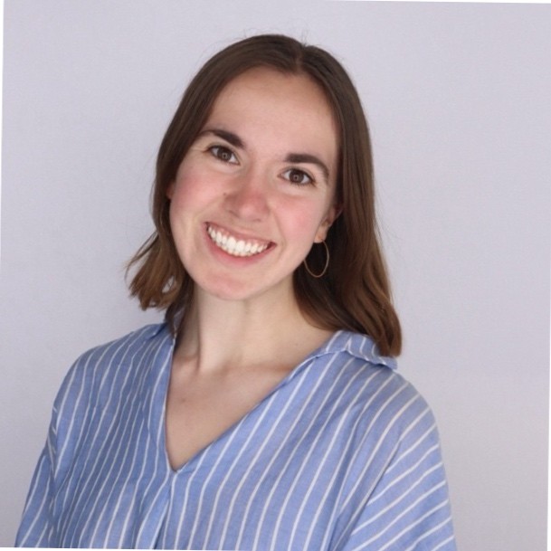 Nora Kraus, National Grid. Woman with shoulder-length brown hair in a blue and white striped shirt, smiling against a plain light background.