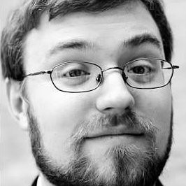 Syd Bishop, Virtual Peaker. Man with glasses and a beard smiling slightly, shown in black and white, with a blurred background.